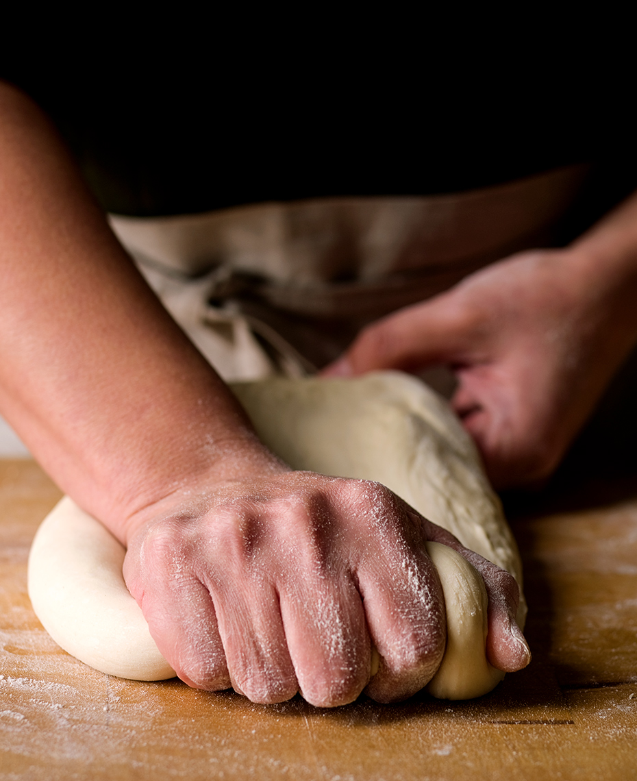 Baker kneading dough on butcher block
