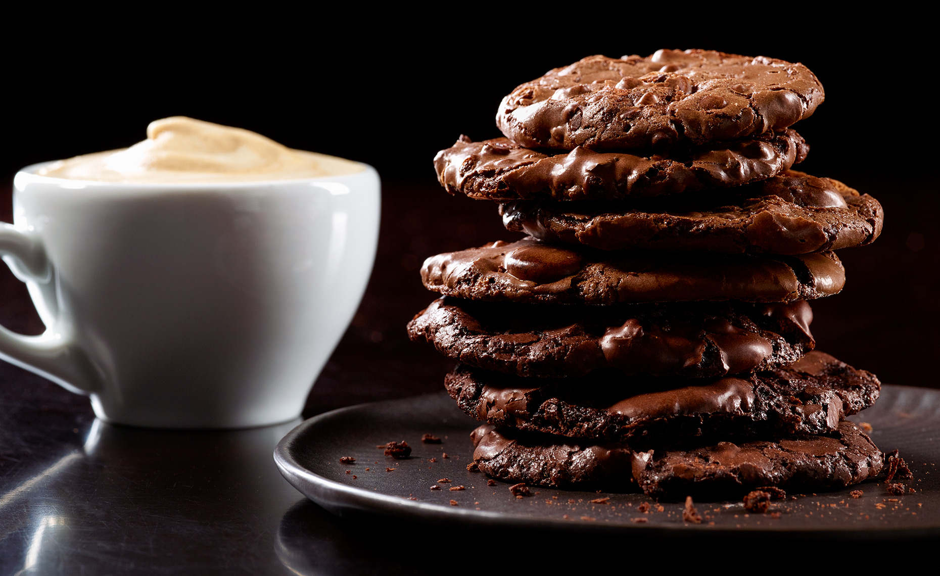 Stack of chocolate chocolate cookies and cup of espresso
