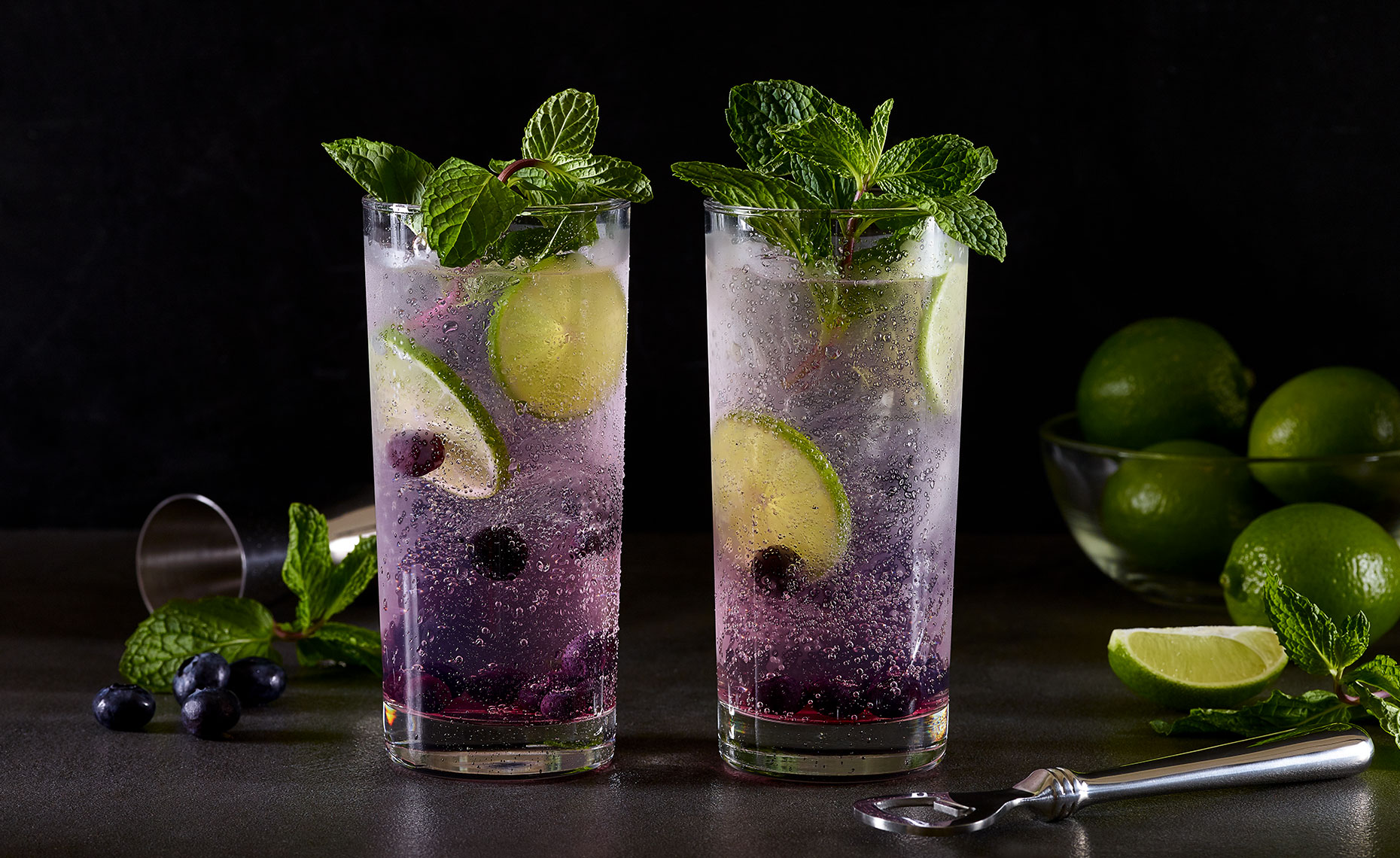 Two glasses of gin and tonic with fresh blueberries and lime