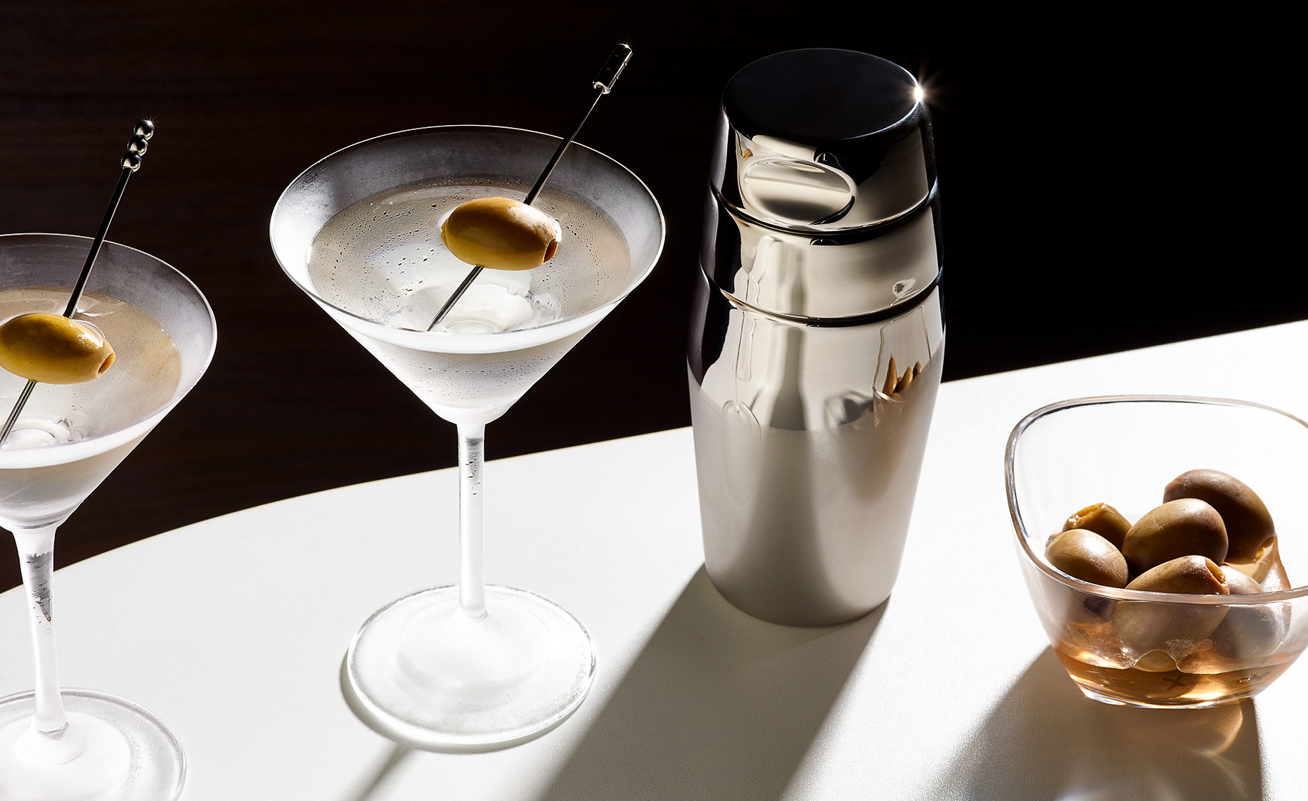 Two martinis with olives and shaker