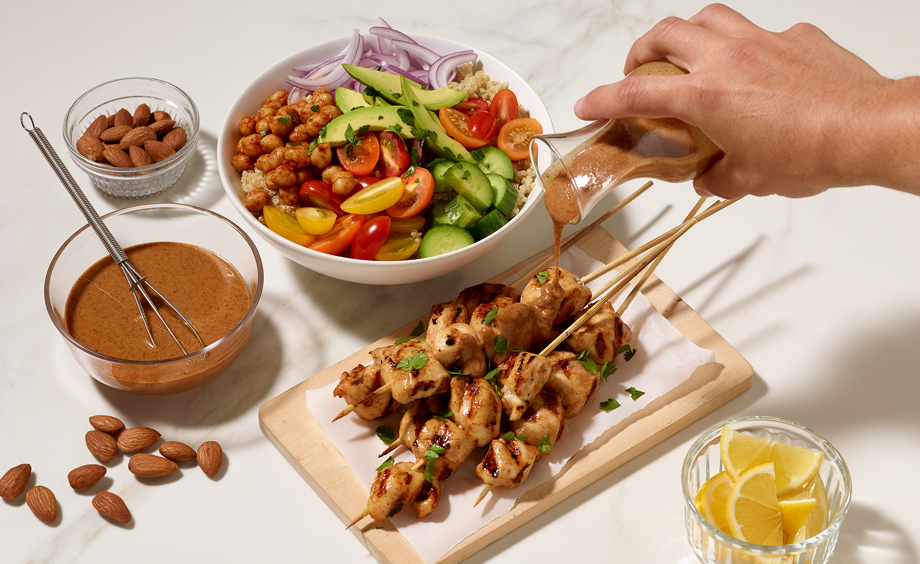 Drizzling almond butter savory sauce on chicken skewers 