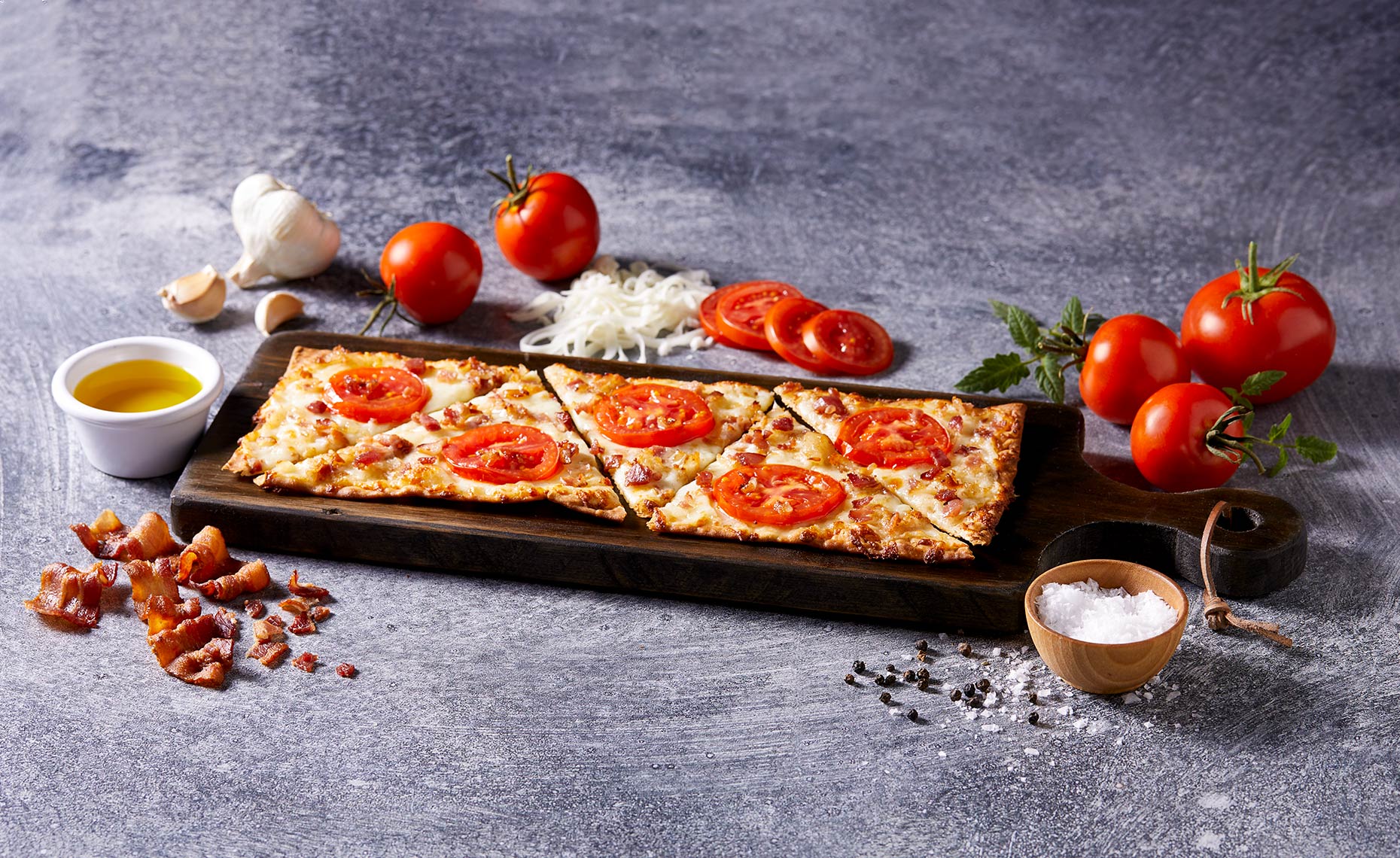 Flat bread pizza on cutting board with ingredients