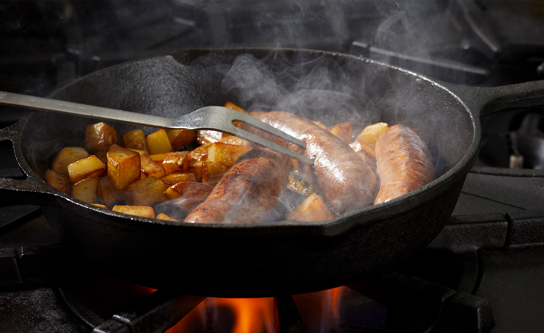 Sausage and potatoes cooking in cast iron pan